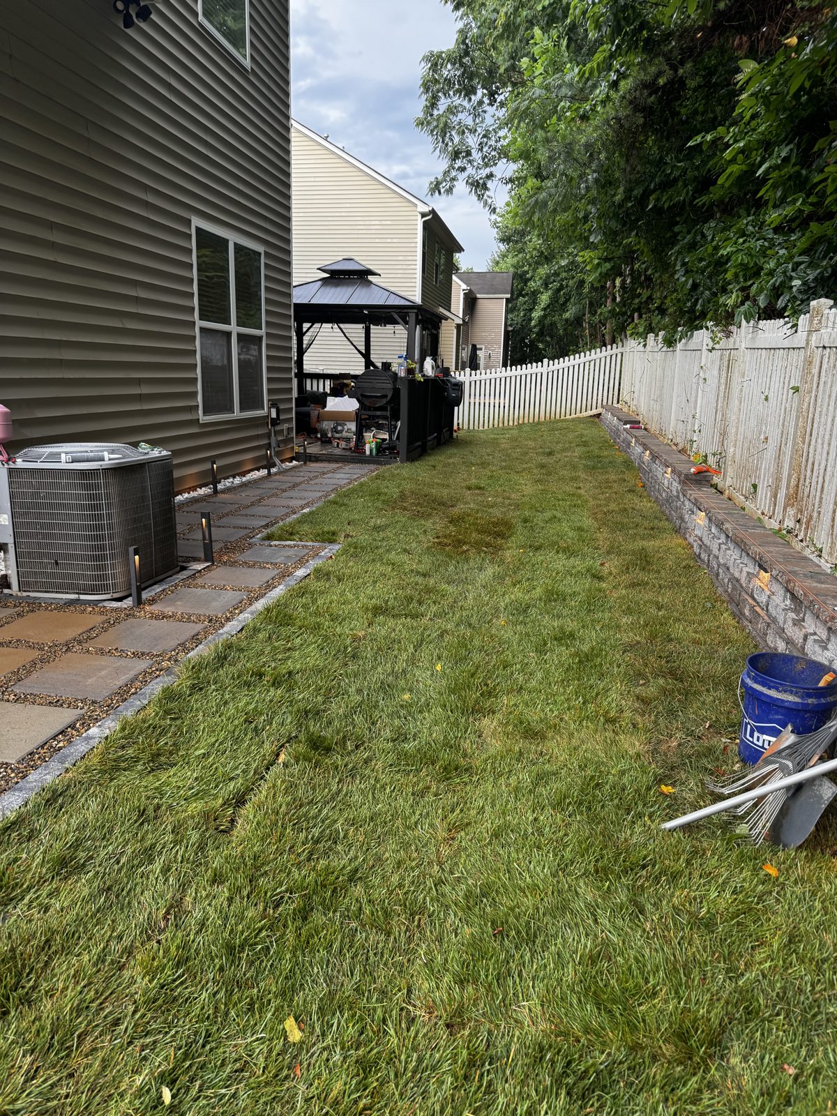 Finished backyard in daylight — green lawn, wall, and walkway
